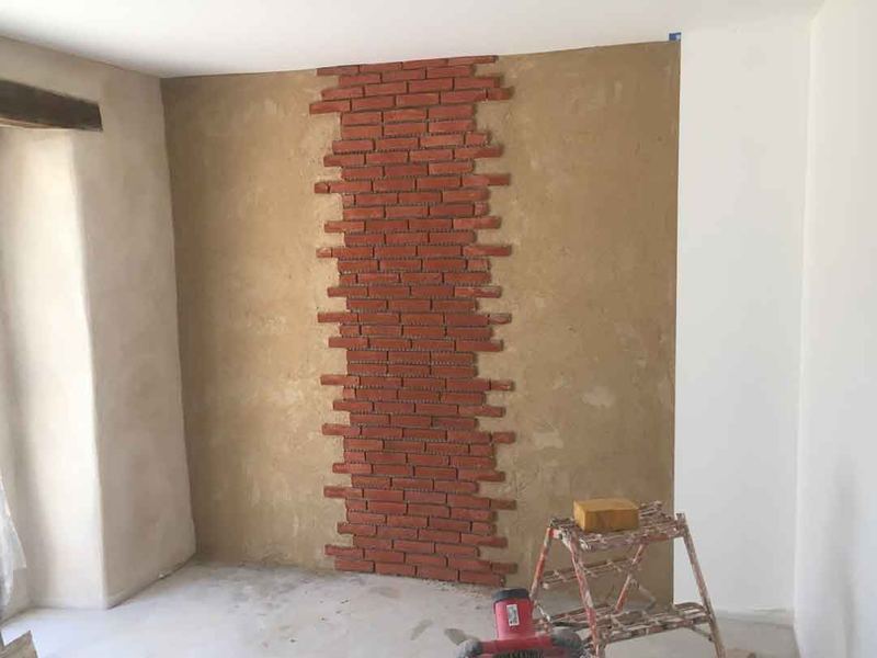 Mur intérieur enduit à la chaux, bande de brique laissée apparente